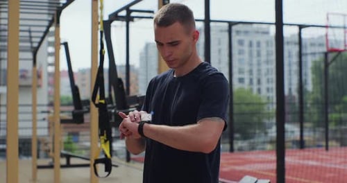 Man Using Smart Watch in Outdoor Urban Gym