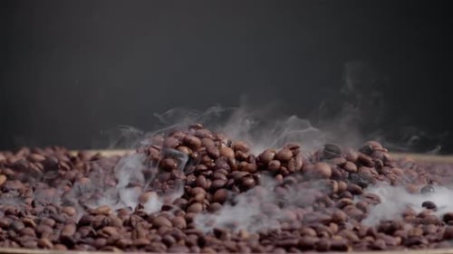 Roasted Coffee Beans Steaming Close Up. Light Smoke Coming From Fresh Brown