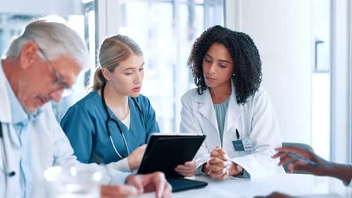 Medical Professionals Collaborating on Tablet in Bright Office