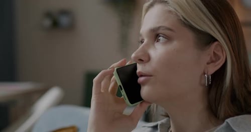 Closeup Portrait of Joyful Blonde Chatting on Mobile Phone Indoors in Apartment in Evening