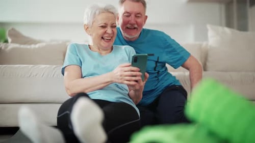 Senior Couple Laughing at Smartphone Content Indoors