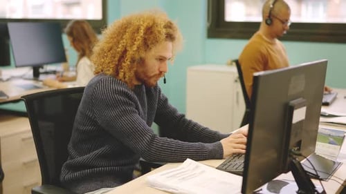 Homme moderne travaillant dans un coworking à l'aide d'un ordinateur et d'un casque