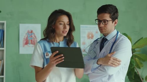 Doctors Discussing Patient Data on Tablet in Office