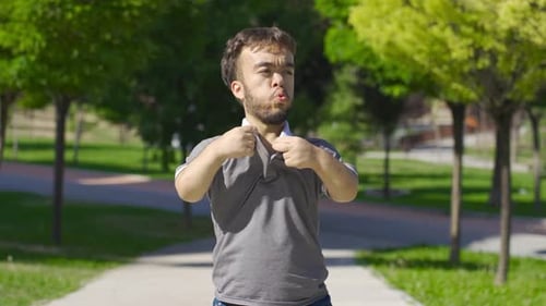 Un jeune homme nain suffoque à cause du soleil et de la chaleur qu'il fait dehors.