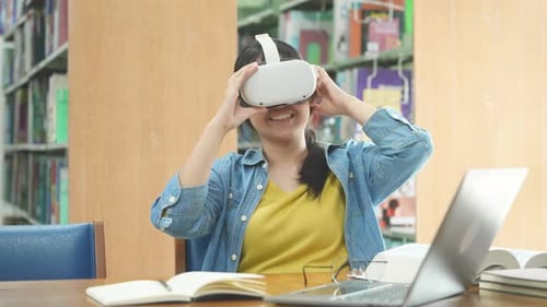 Young Asian female high school student using virtual reality headset in the library.