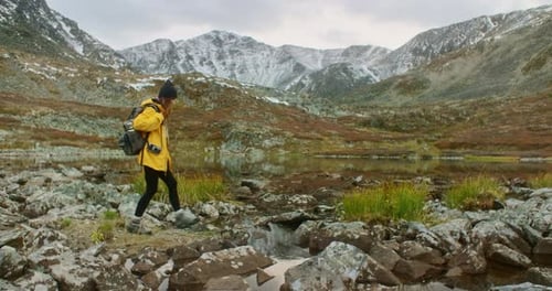 Woman Hiker Crossing Stream Near Mountain Lake in Autumn