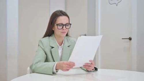 Enthusiastic Woman Reviews Documents in Bright Office