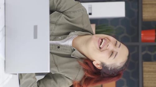 Woman with Red Hair Laughing at Laptop