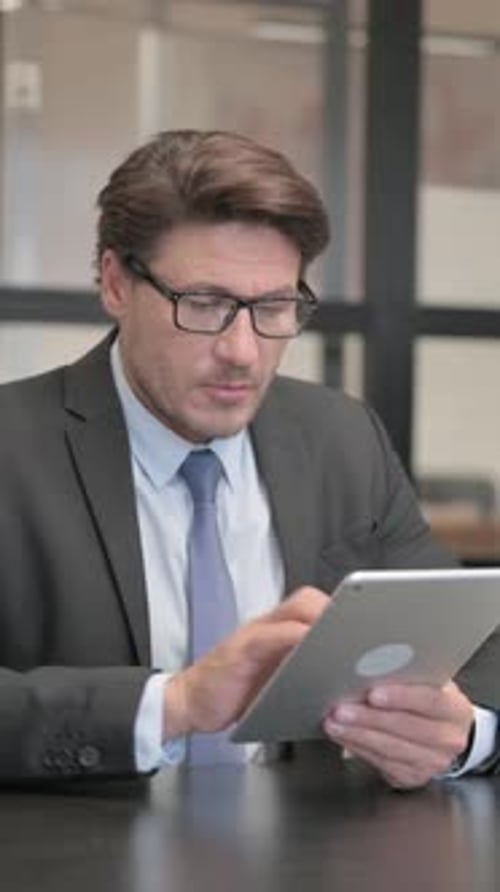 Businessman Using Digital Tablet in Office, vertical