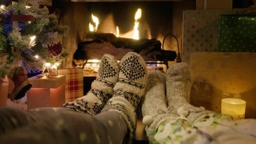 First Person View on Couple Feet in Cozy Christmas Woolen Socks at Fireplace