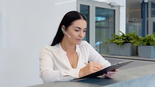 Welcoming Woman Taking Notes at Reception Desk