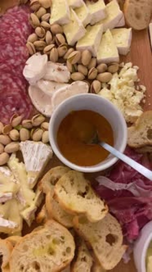POV de fromage en bois et planche à viande, charcuterie avec charcuterie, pistaches, pain frais, gourmand