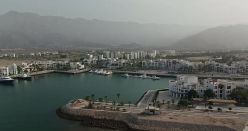 Abgewinkelte Drohnenperspektive des Sifah-Komplexes, des Jachthafens und der Küste, Oman