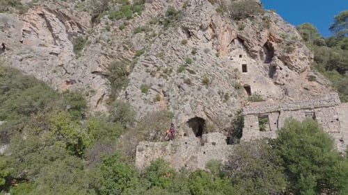 Ancient stone ruins built into a rocky mountainside with lush green trees