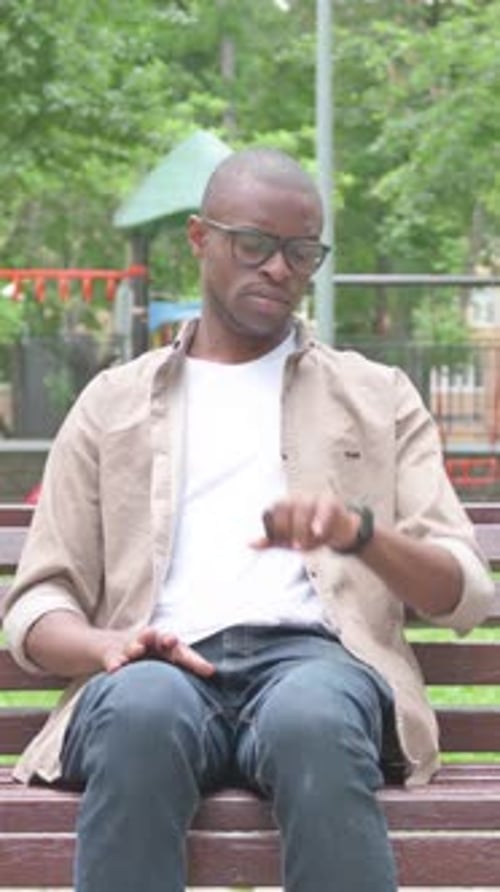 Man Sitting on Park Bench Checking his Watch