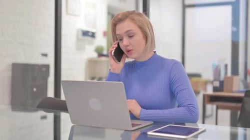 Woman Talking on Phone While Using Laptop