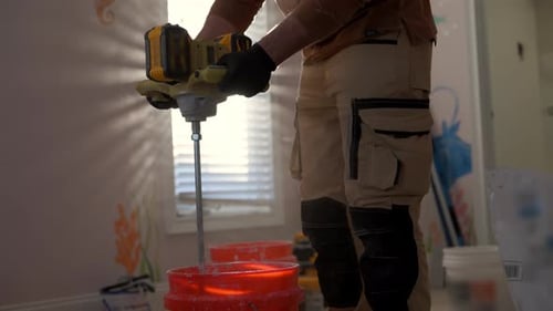 Man mixes plaster with electric mixer in bucket