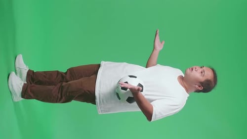 Full Body Of Asian Man With A Ball Making Fun Of The Losers While Cheering Soccer On Green Screen