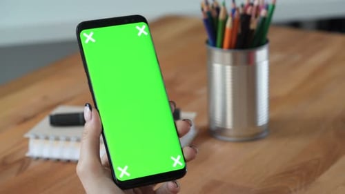 Person Hold Cellphone With Green Screen Display In Hand In Workplace. Close Up Concept Of Copy Sp...