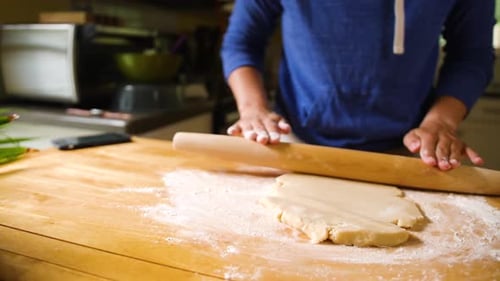 Close up hands rolling dough out on floured surface baking a pie