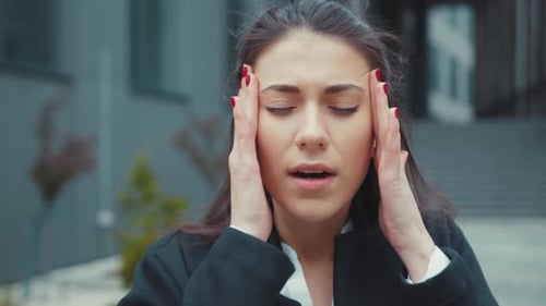Woman Massaging Temples for Headache Relief Outdoors