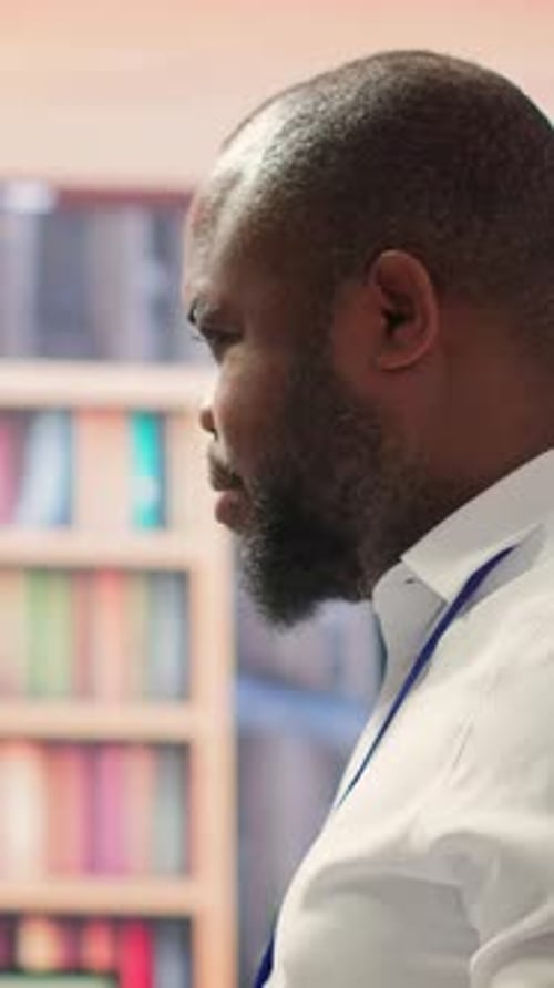 Man Speaking With Bookshelf in Home Setting