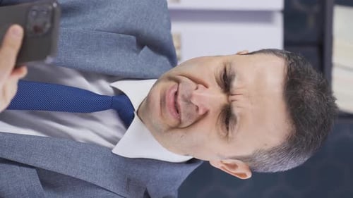 Vertical Video of Mature businessman sitting at office desk frustrated with frustration.