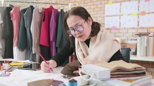 Asian female fashion designer works by idea drawing sketches for a dress design.
