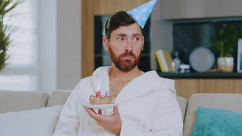 Portrait Sad Young Man Celebrates Birthday Alone Hold Cake Sitting at Sofa in the Living Room During