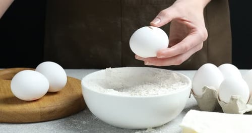 Breaking an Egg into Flour Bowl for Baking