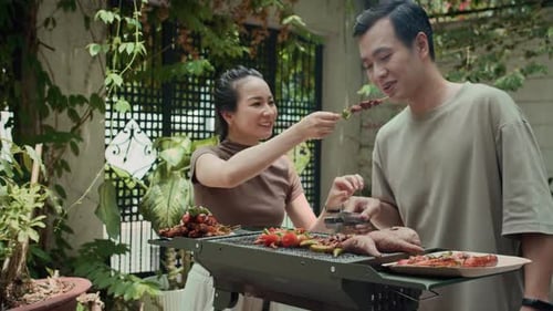 Couple Grilling Vegetables and Meat at a Backyard Barbecue