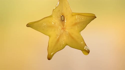 Makroaufnahme von fließendem Karambolensaft aus halbierter Carambola-Sternfrucht in Zeitlupe