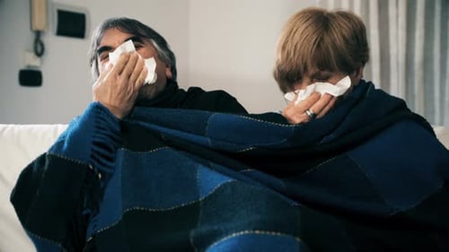 Sick Couple with Cold Blowing Noses on Couch