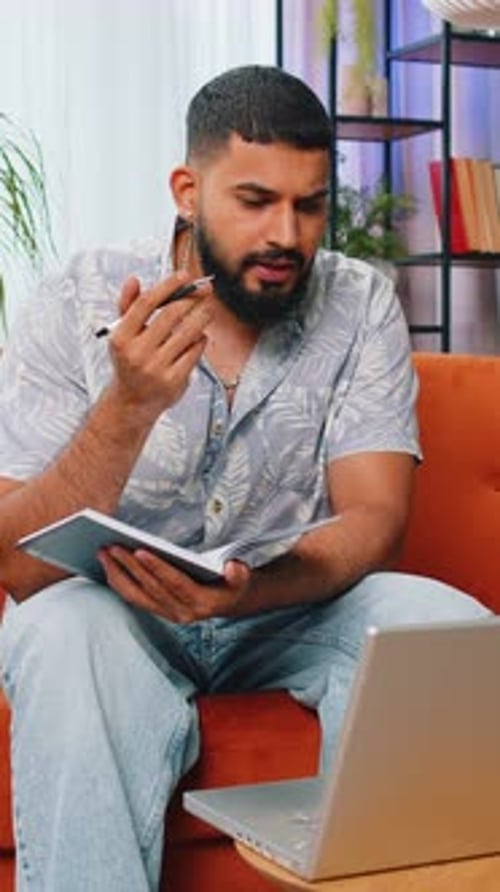 Man Working From Home with Laptop and Notebook