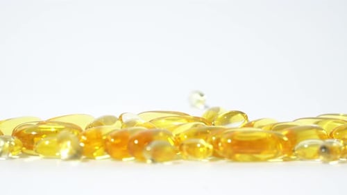 Golden Capsules Falling onto White Surface