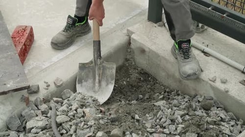 Arbeiter gräbt mit einer Schaufel elektrische Leitungen in den Boden Mann gräbt mit einem Schub einen Graben in den Boden