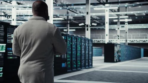 Engineer Walking in Data Center Using Device to Configure Hardware