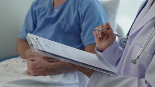 Doctor Taking Notes on Patient Chart in Hospital