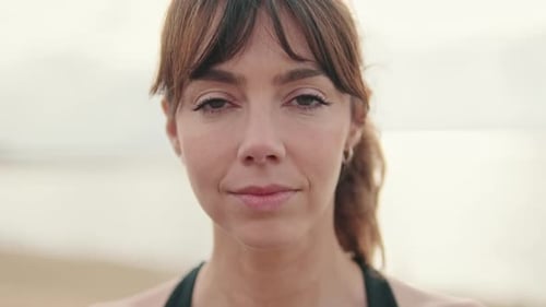 Close-up of european smiled girl in sportswear against the sea with her eyes closed