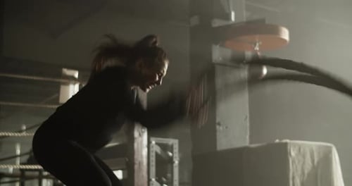 Strong Athletic Woman Training with Battle Rope in Gymnasium