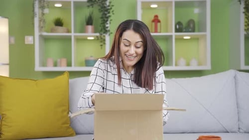 Woman Opening a Gift in Living Room, Smiling