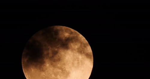 Golden Full Moon Behind Passing Clouds at Night