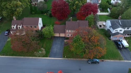 Houses in USA neighborhood. Autumn trees in evening light. Aerial truck shot.