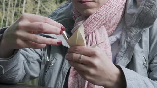 Weibliches Mädchen beendet Origami-Papierschwan, Nahaufnahme