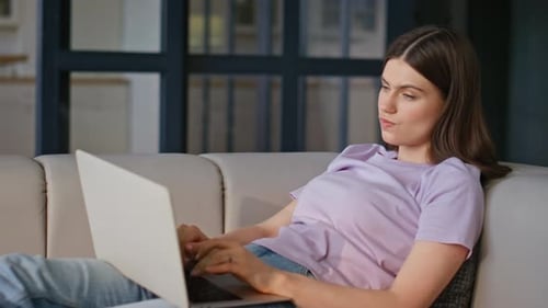 Woman Uses Laptop on Light Colored Sofa