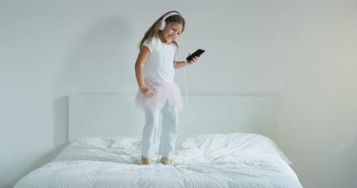 Child Dancing and Jumping on Bed at Home