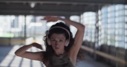 Woman Dancing with Headphones in Urban Setting