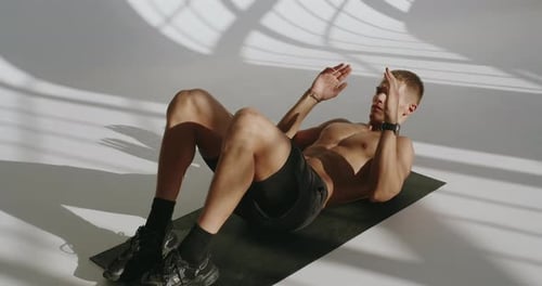 Athletic Young Man Training Abs in Studio with Dramatic Lighting