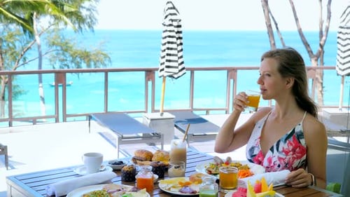 Young Woman Drink Orange Juice Sitting in Cafe in Resort on Summer Vacation
