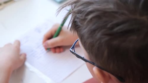 Child Writes with a Pen on White Paper